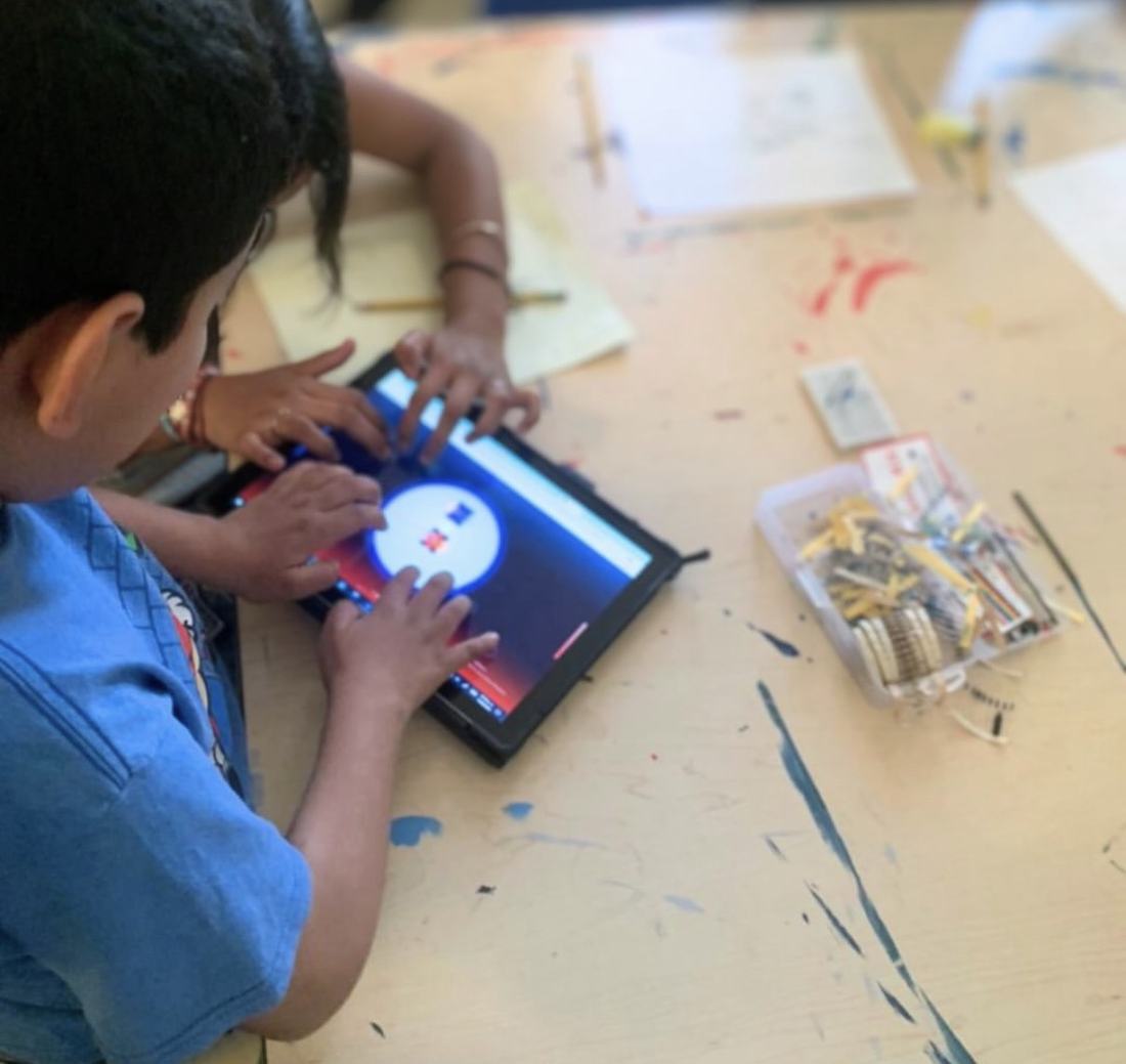 Alumno usando el simulador de CultivaTec desde una tablet, junto a la caja de componentes del kit