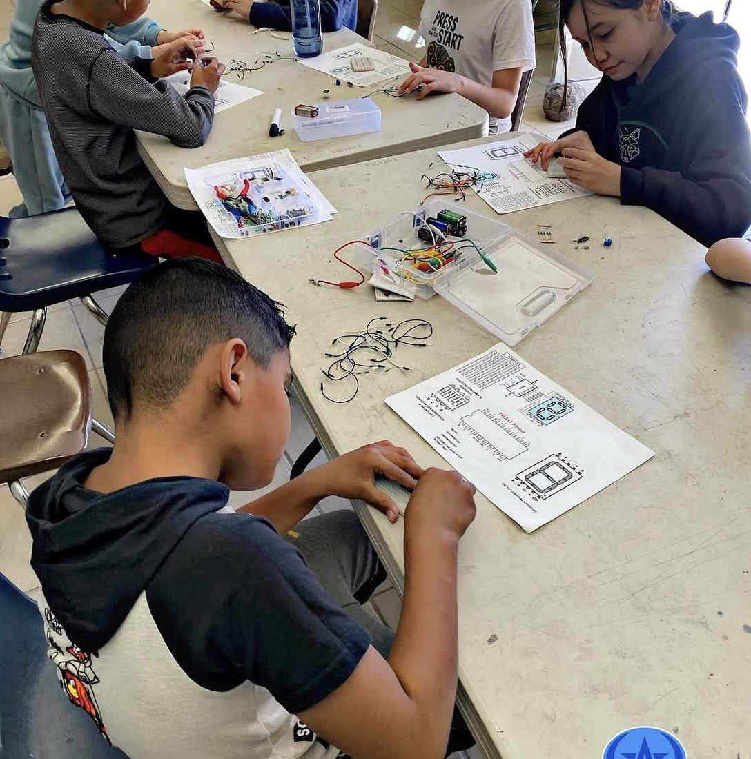 Alumnos resolviendo la hoja de reto de la sesión con los componentes del kit sobre la mesa