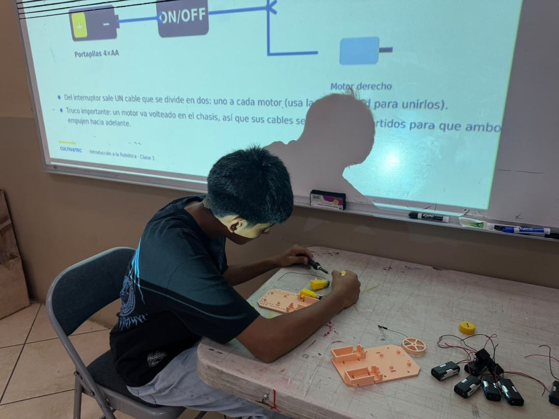 Alumno conecta los motores de su robot siguiendo el diagrama proyectado en la clase de robótica de CultivaTec
