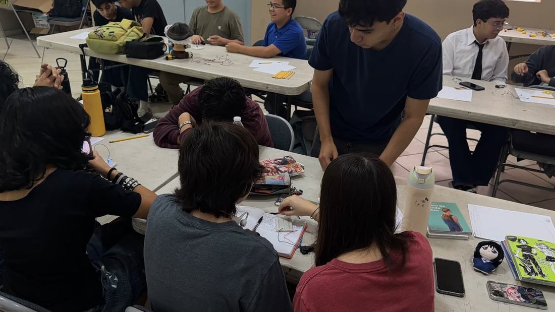Instructor de CultivaTec apoya a un equipo de alumnos que arma su circuito sobre la mesa de trabajo
