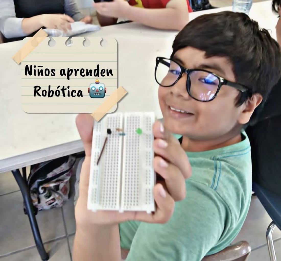 Niño sonriendo mientras muestra la protoboard con el circuito que acaba de armar en un taller gratuito