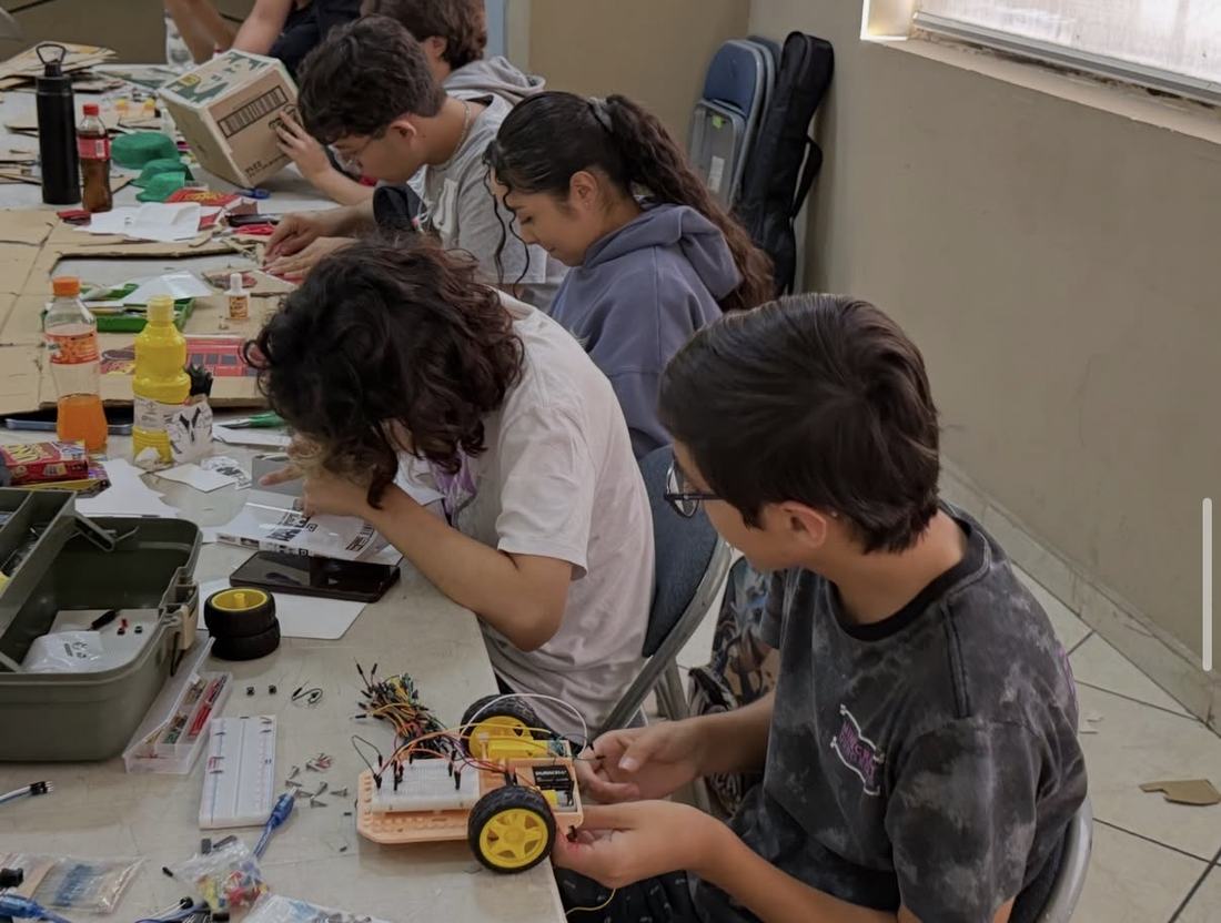 Niños de primaria arman entre todos un carro robot con protoboard, motores y ruedas en un taller de CultivaTec