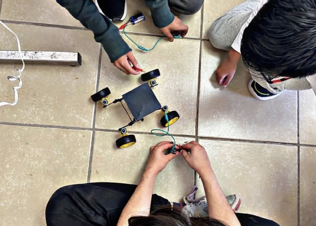 Alumnos probando en el piso el recorrido de un robot móvil armado con el kit de CultivaTec