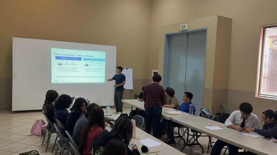 Aula llena de alumnos durante un taller de robótica de CultivaTec, con la presentación proyectada al frente